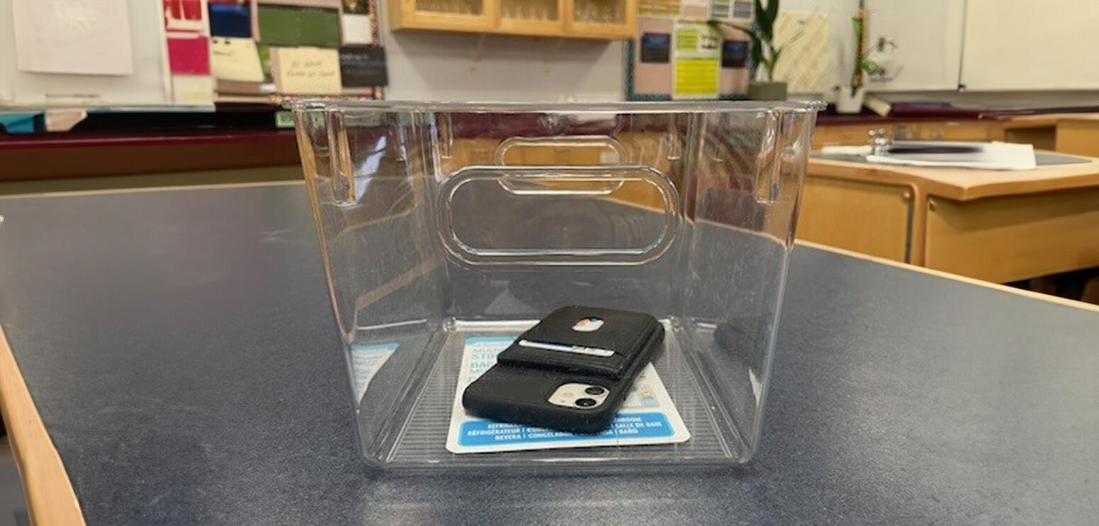 Cellphone sitting in transparent bin on desktop
