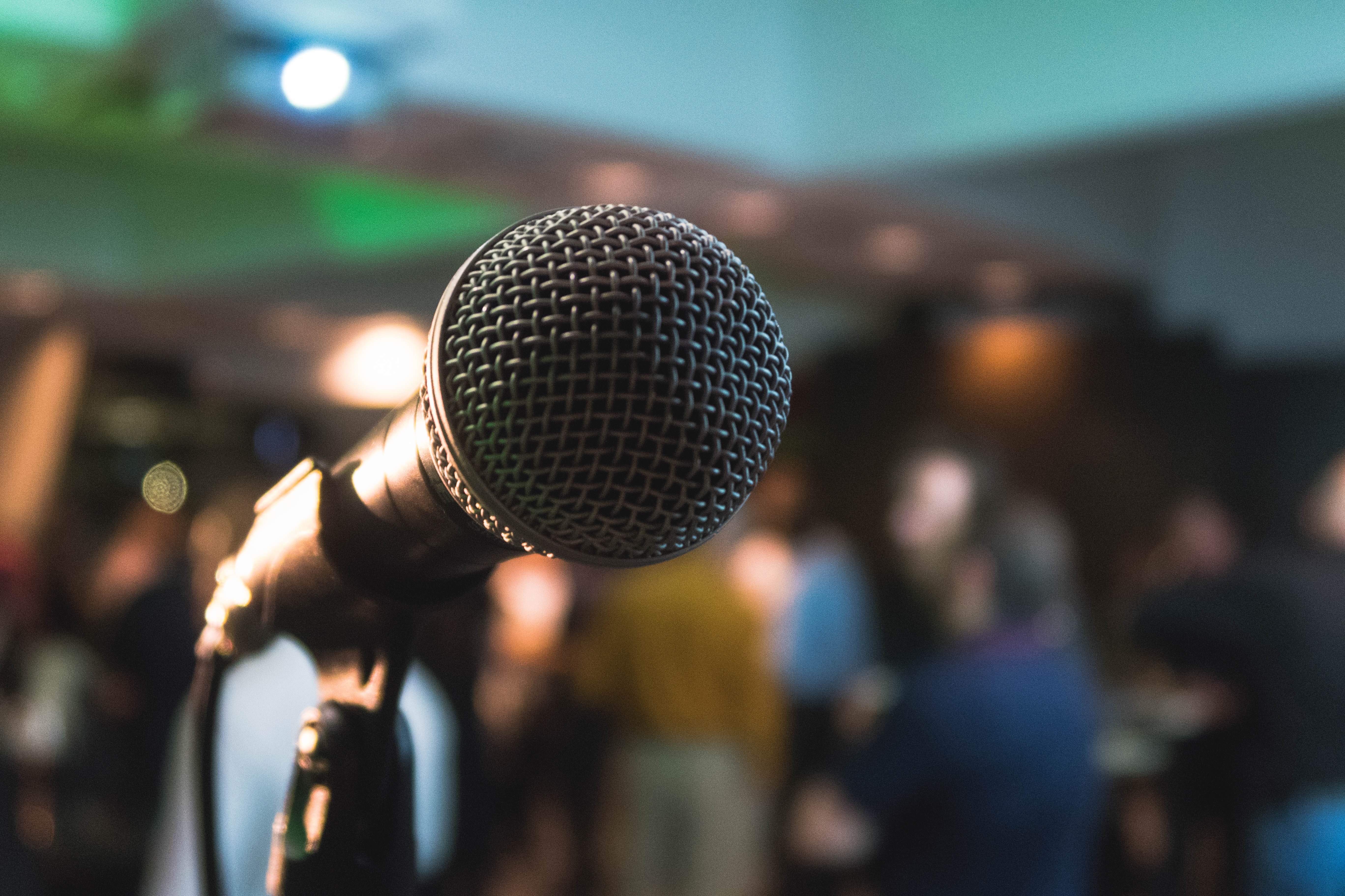 A close-up shot of a microphone on a stage in front of a blurry crowd