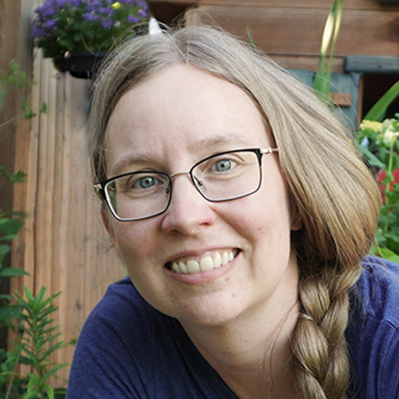 Profile picture of Caroline Barlott wearing a purple shirt in her garden. 