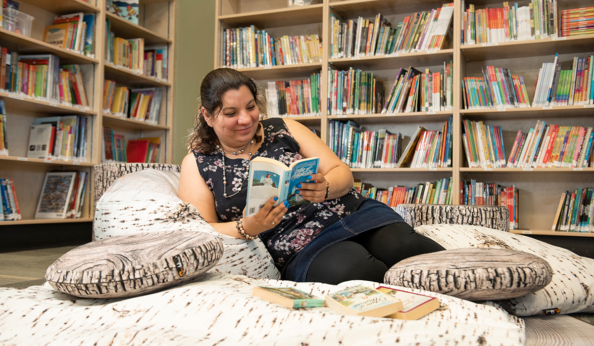 Women seated in a nest of pillows reading a book in a children's library.