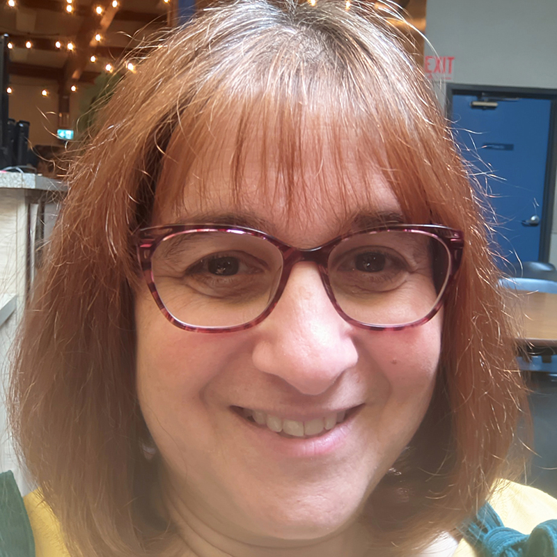 Profile picture of red haired women with glasses, smiling.