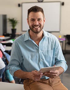 Young male teacher with class working in a group behind him