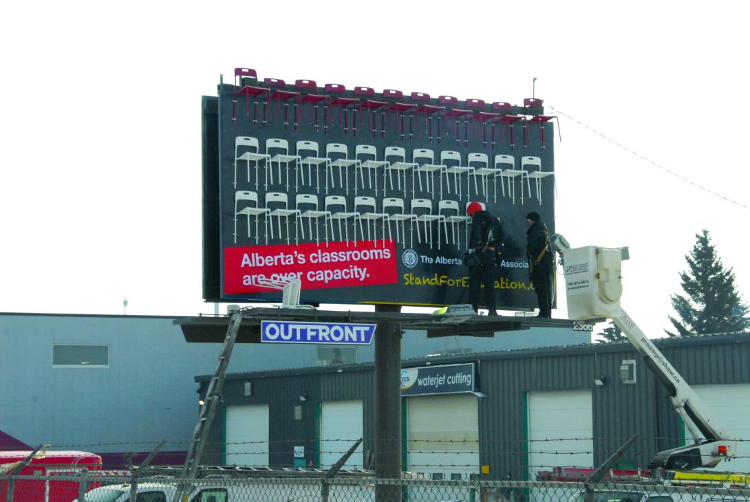 Workers install chairs on an ATA billboard