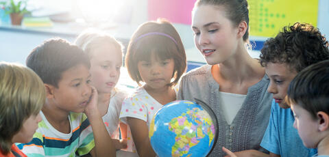 A teacher shows a globe to her students